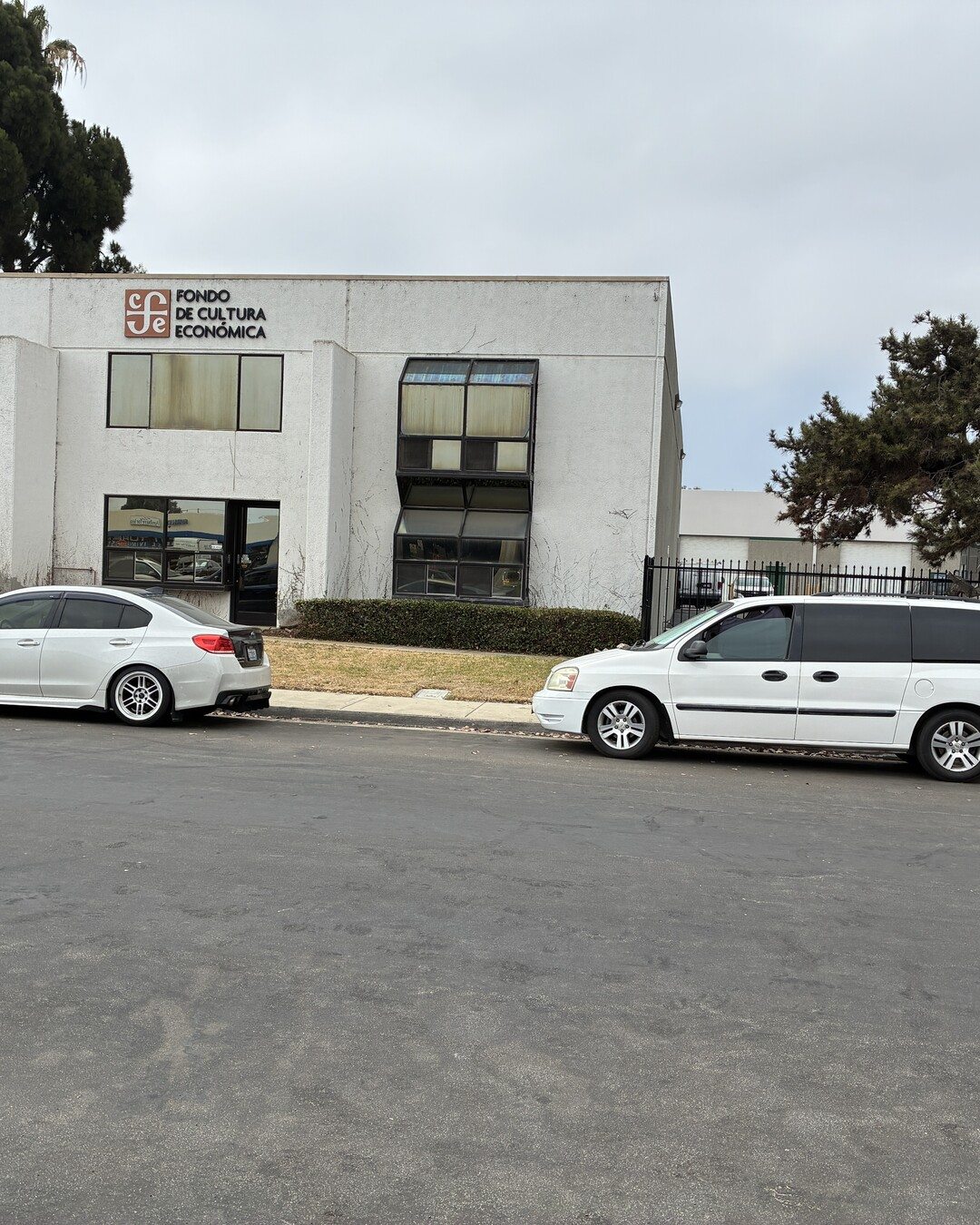 The original building at 2293 Verus Street before renovation: weathered white stucco and dated angled windows.