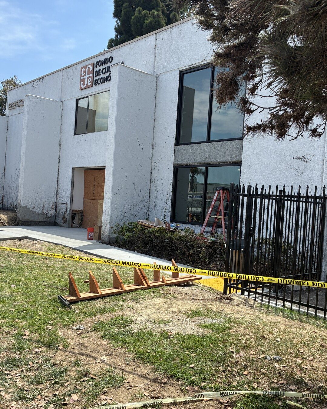 The building mid-renovation: new black-framed windows installed, old signage removed, and a fresh concrete walkway.